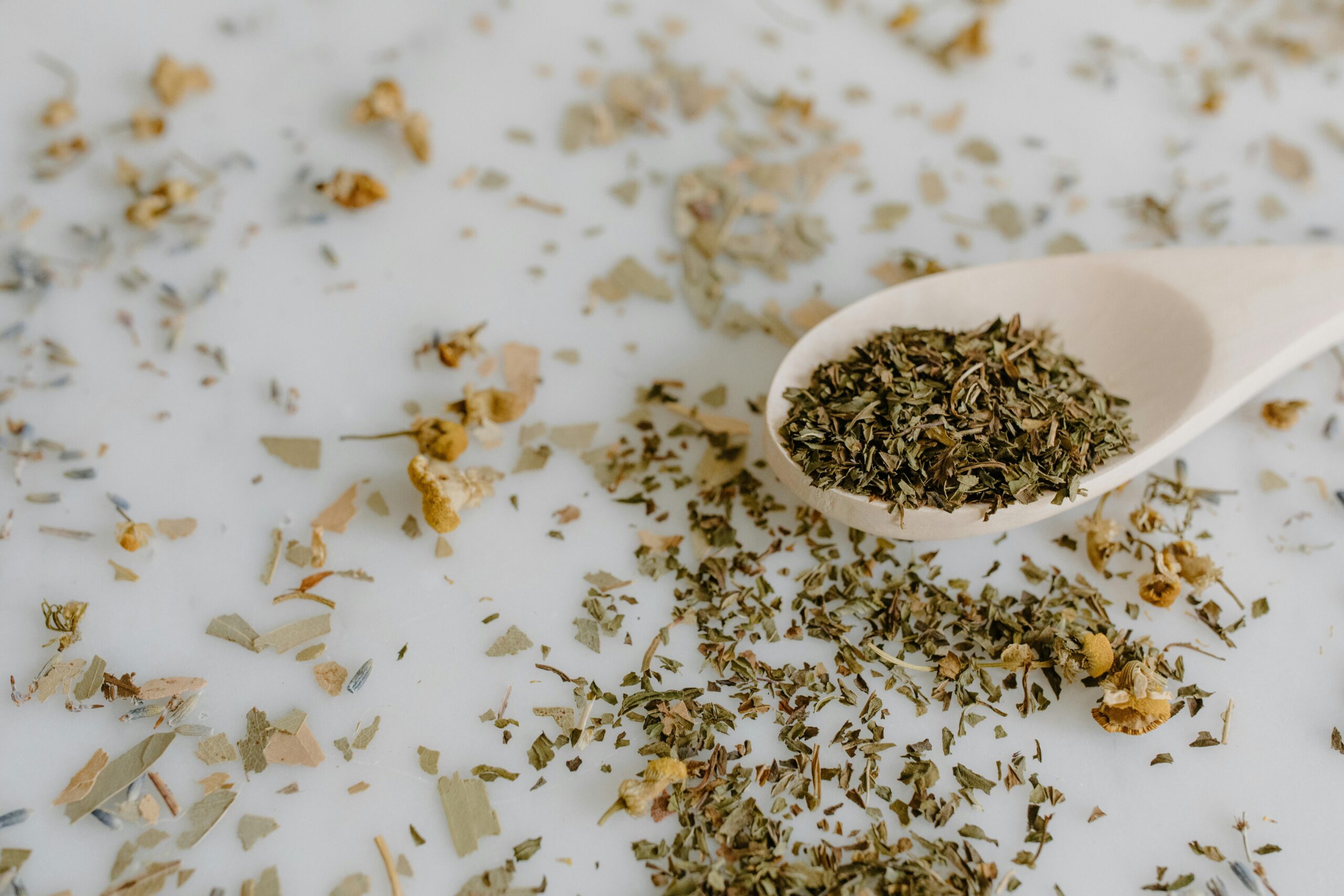 Close-up of dried herbs and floral elements with wooden spoon.